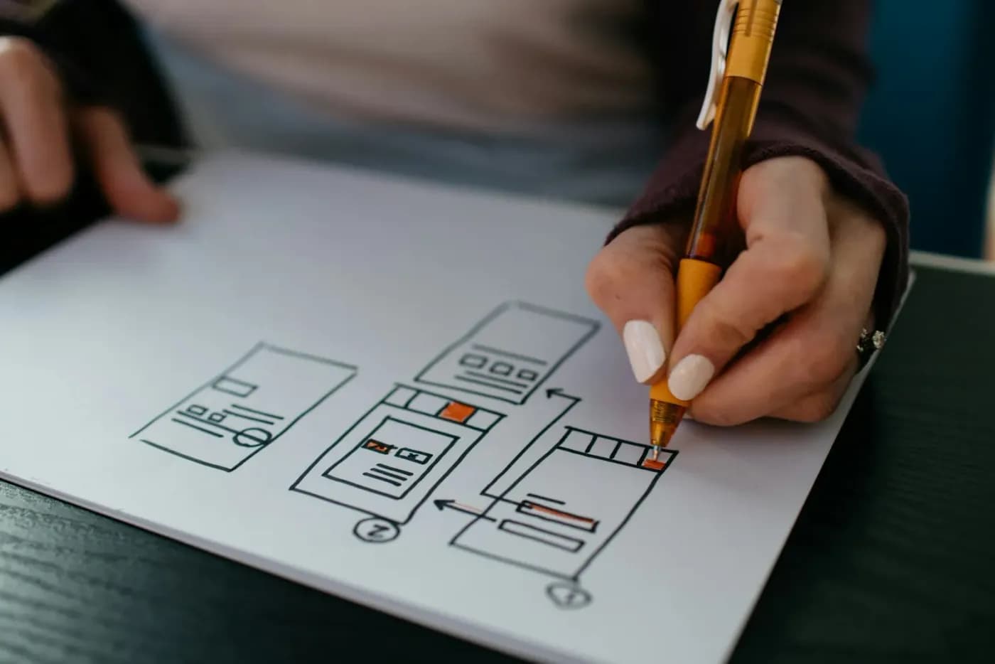 A hand sketching an app’s screens on paper